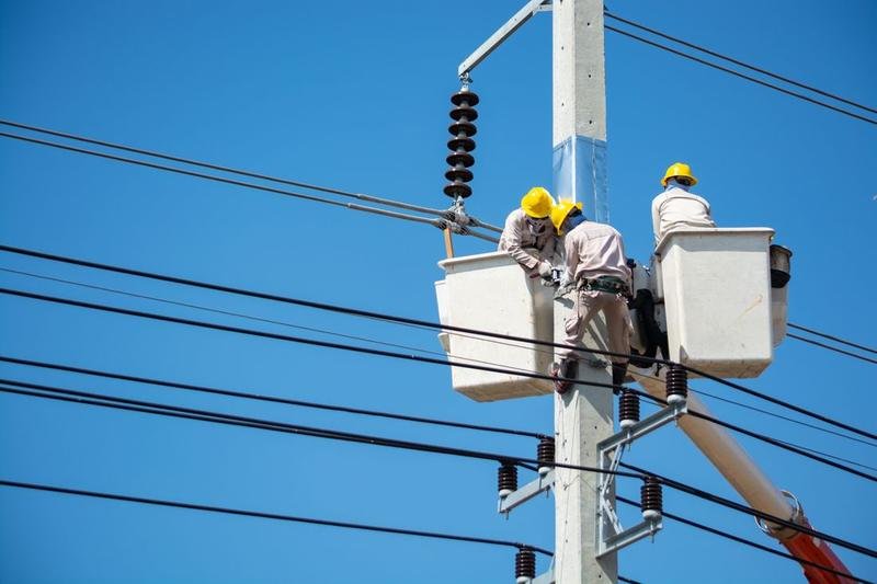 Linemen working on three-phase overhead power lines